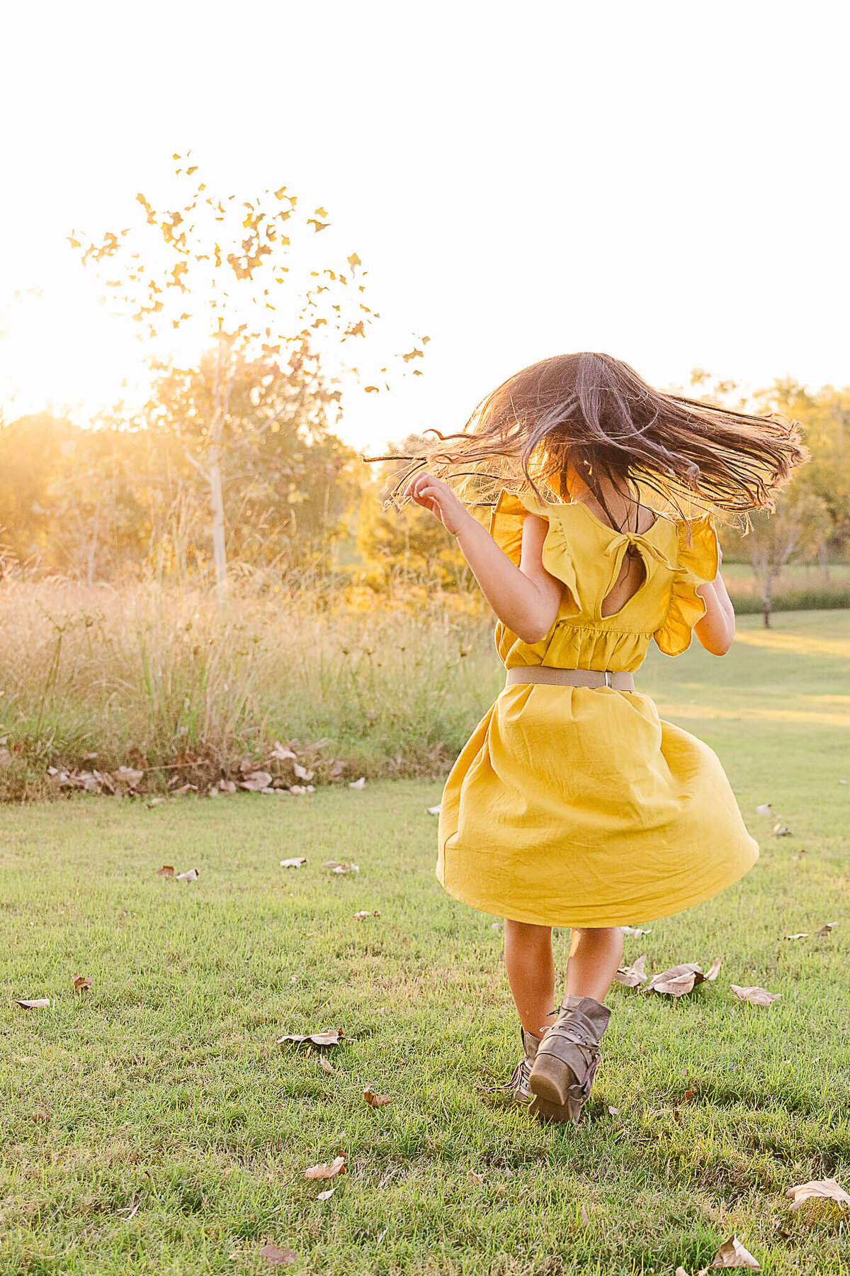 Girl dancing in yellow dress with sun flare
