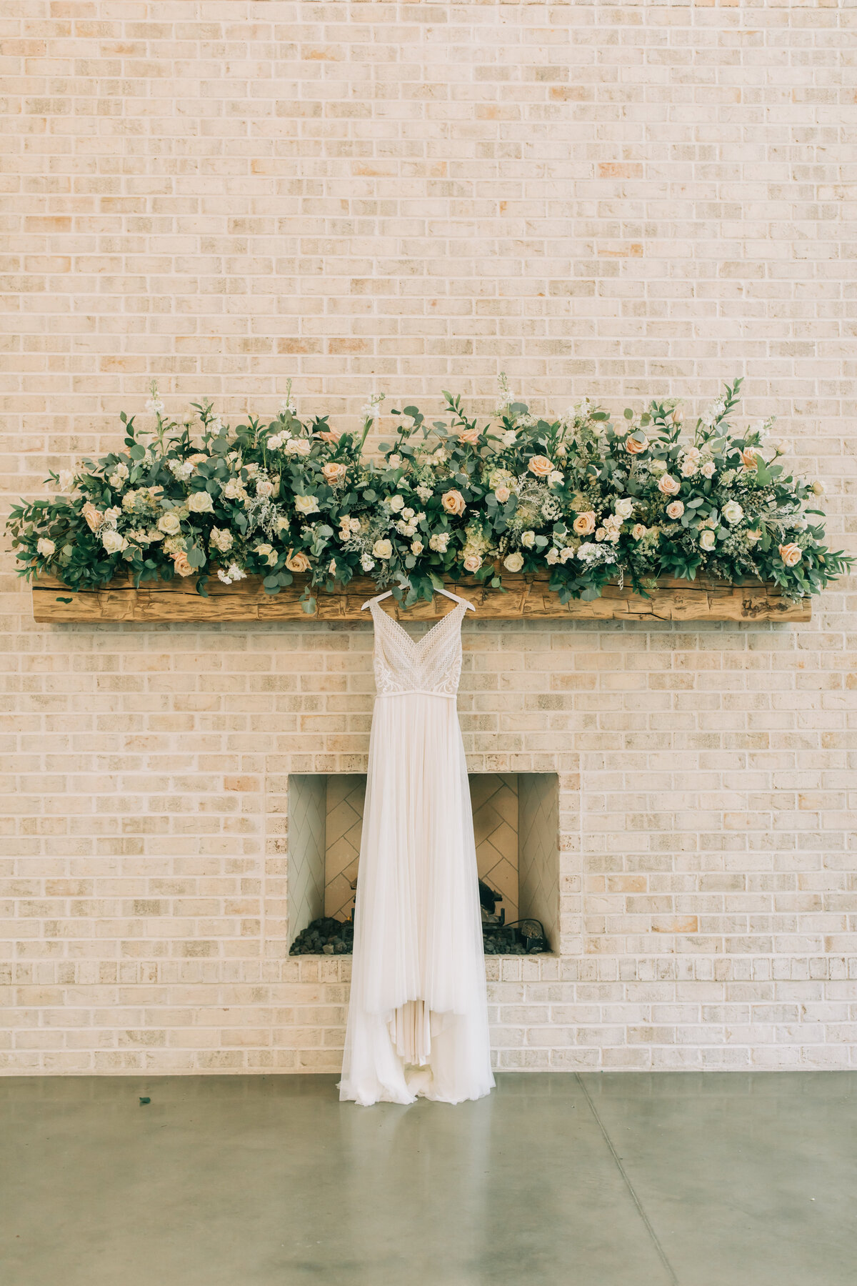 blush flower arrangement on mantle with wedding dress