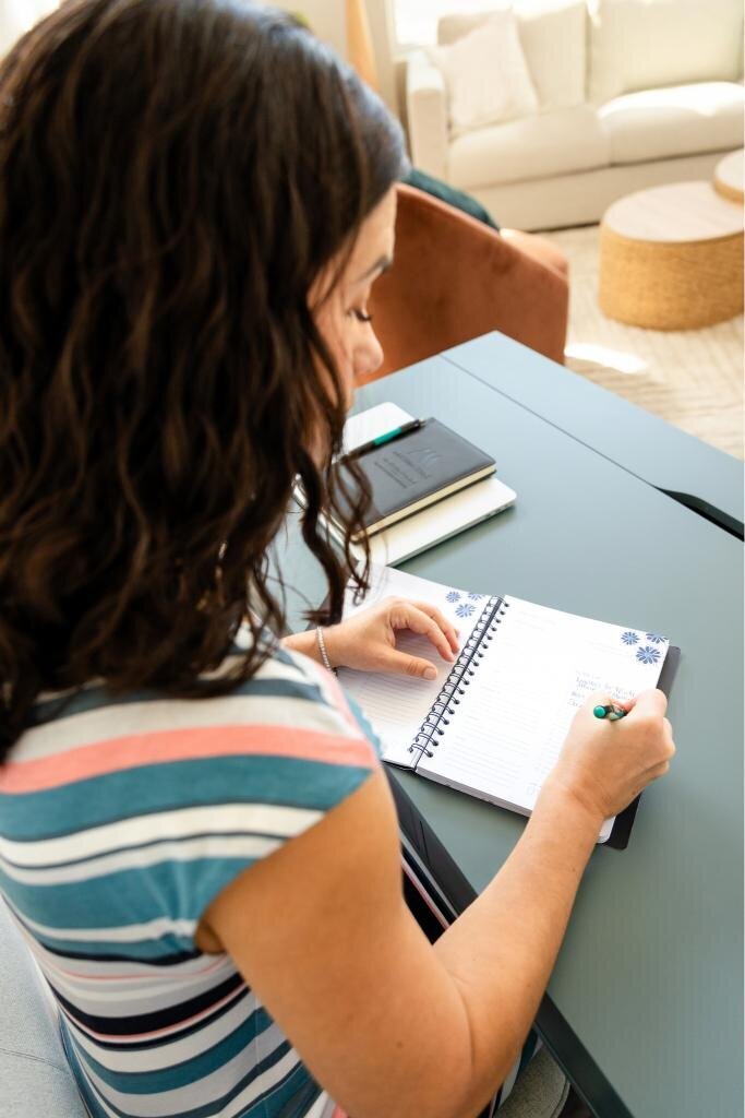 Angie writing in a notebook, perfect for personal branding content on productivity and professional organization.