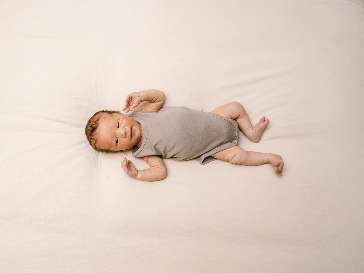 A baby laying on their back and winking.