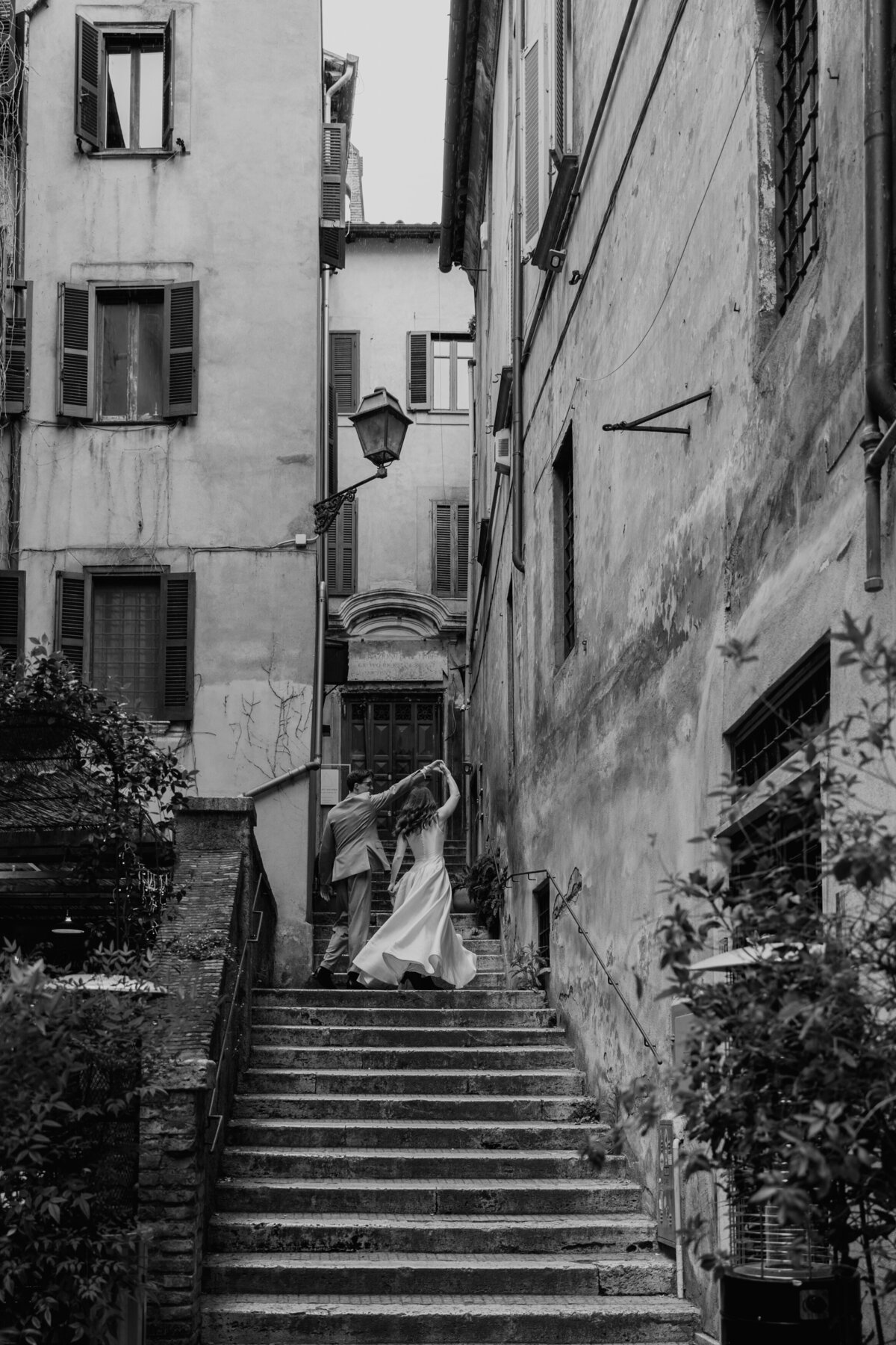 Couple dancing through cobblestone alley in Rome.