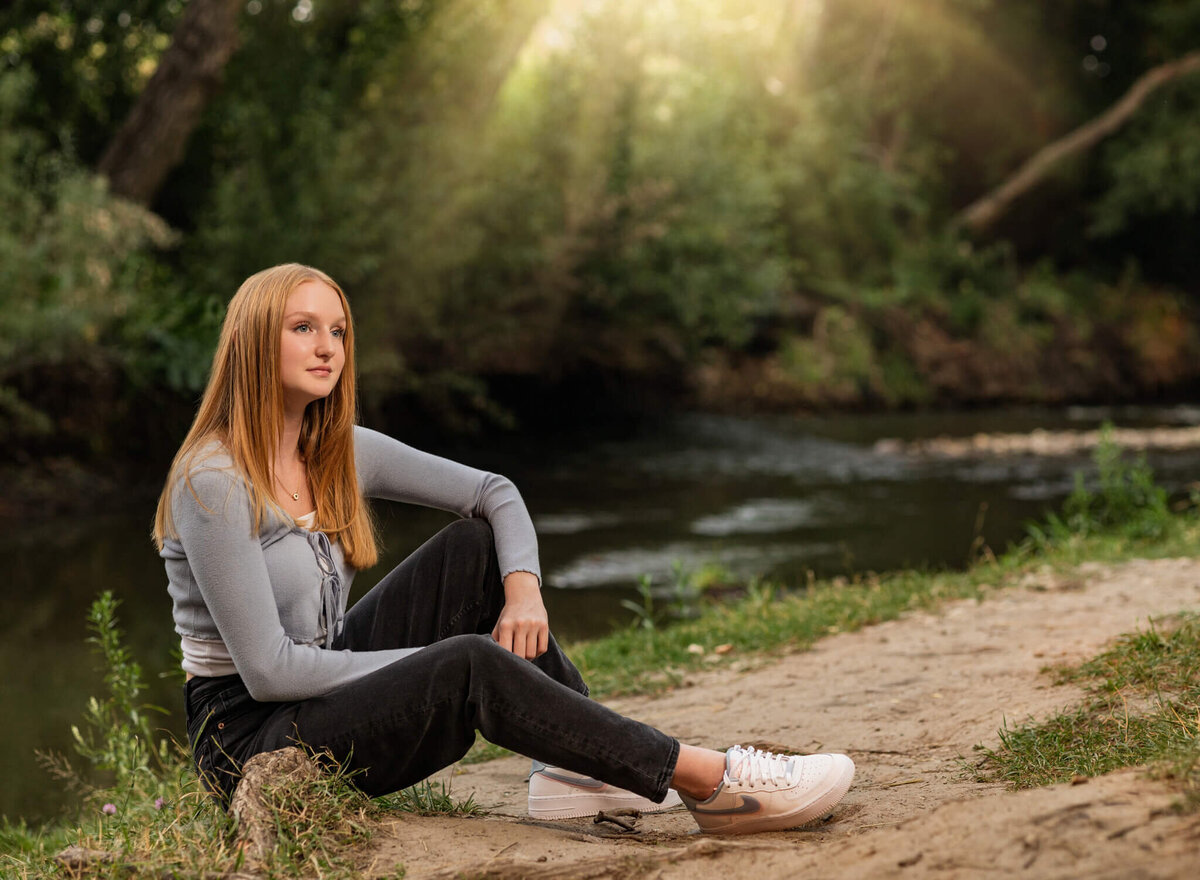 high school senior girl sitting near a  creek