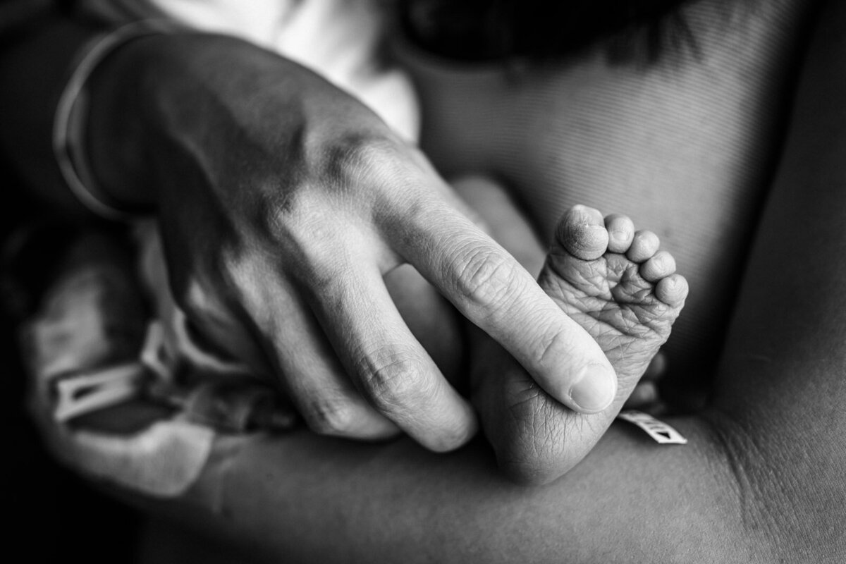 mom holding tiny newborn foot in hospital
