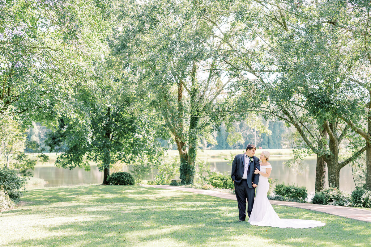 bride and groom standing under trees