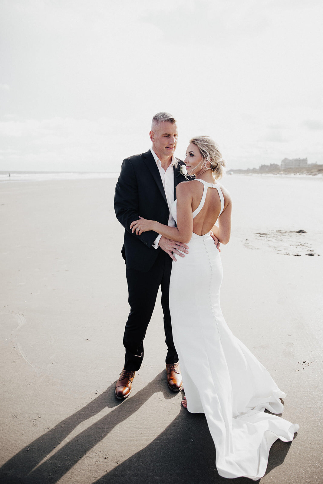 Elegant wedding couple standing at beach casting shadows