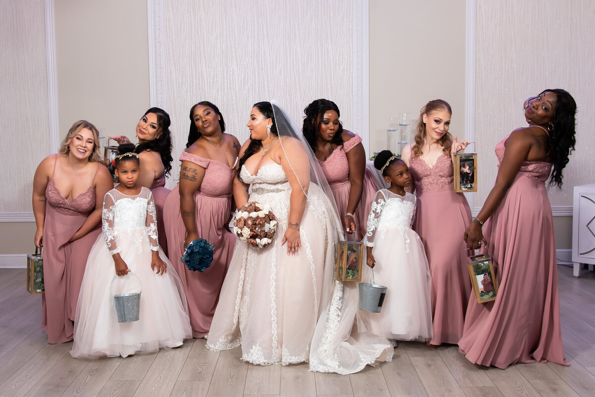a bride, her mini brides and her bridesmaids dressed in blush in a cute pose
