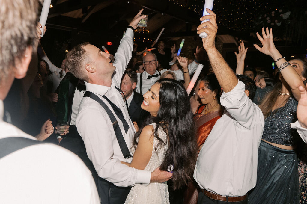 Bride and groom surrounded by guests on the dance floor under twinkle lights and glow sticks at Old Edwards Inn.