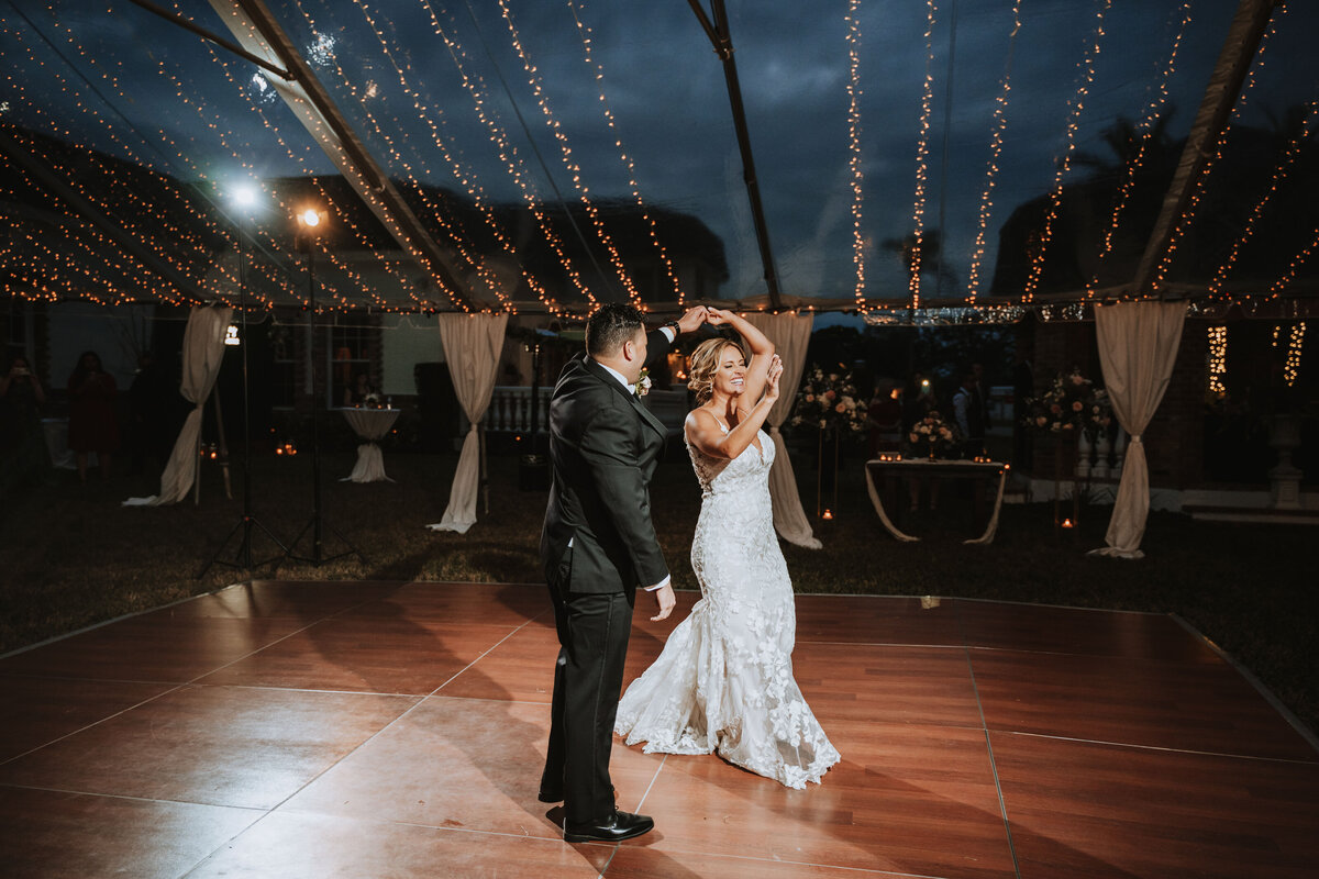 groom spins bride during first dance under a lighted tent at a private residence in clearwater florida