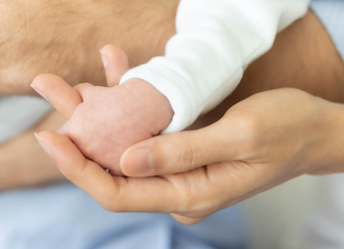 A close-up of a newborn’s tiny hand wrapped in a parent’s gentle grasp during an intimate Florida Keys portrait session.
