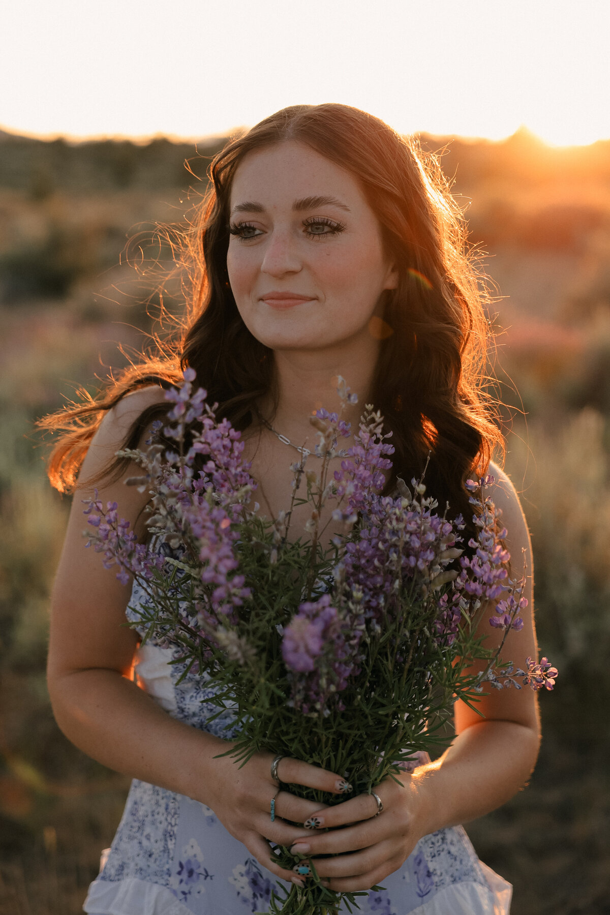 Sunset Senior Session Holding Wildflowers in Blooming Desert Field