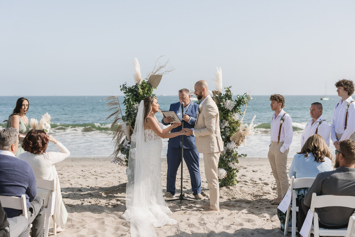 Bride and groom holding hands at ceremony on beach at Hilton Beachfront Resort Santa Barbara