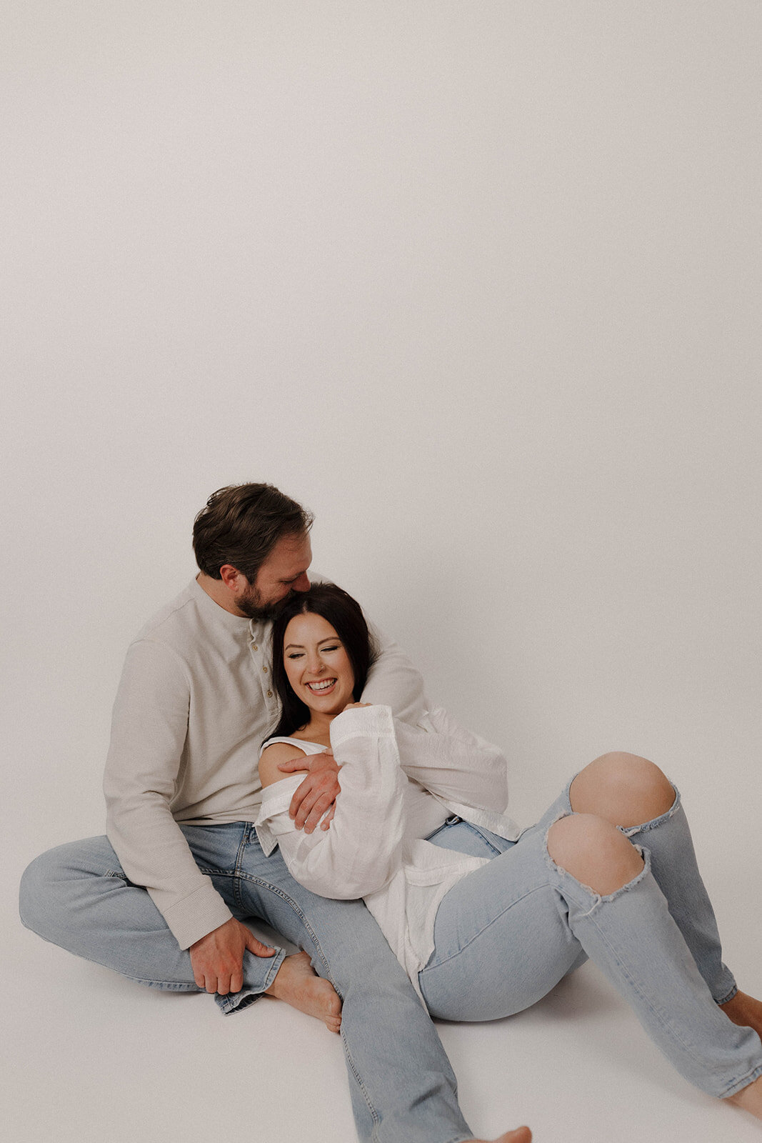 Intimate, playful moment shared by engaged couple during their studio session, photographed in an editorial and candid style ideal for modern couples.