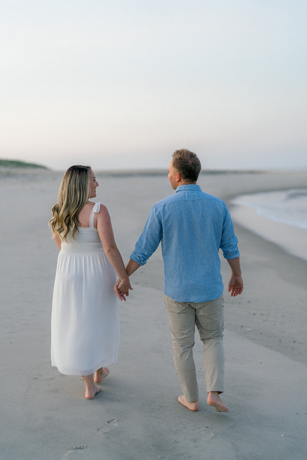 A couple holding hands and walking on the beach in Cape May, New Jersey