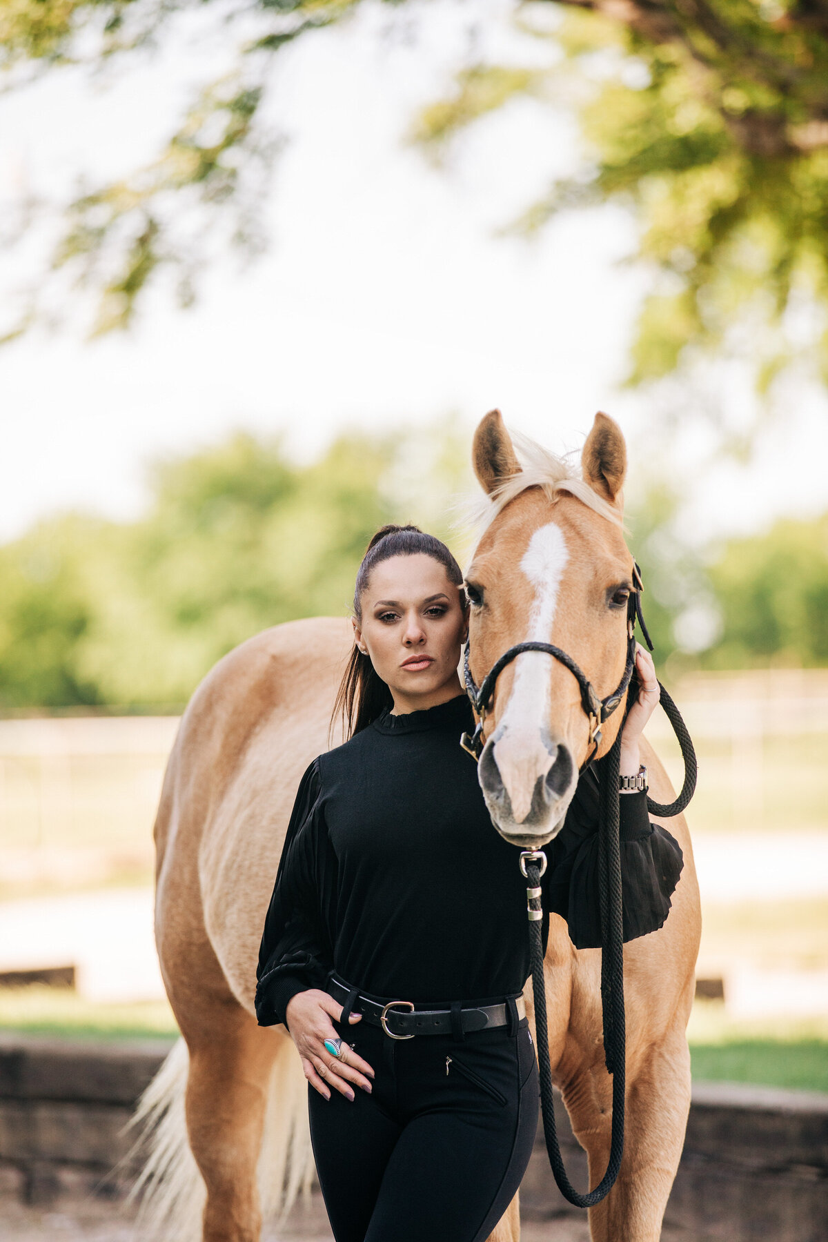 brunette lady in all black with her palomino horse