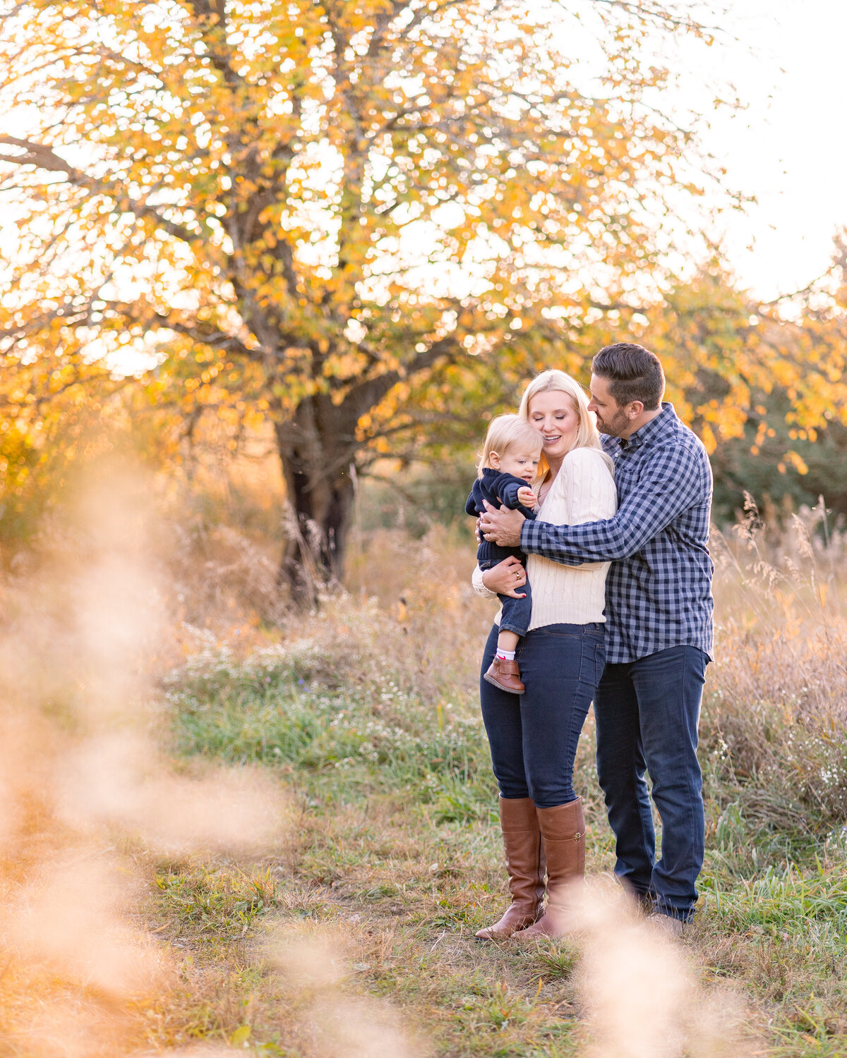 mom and dad cuddling with baby at Kensington Metropark Milford Michigan on a warm fall evening