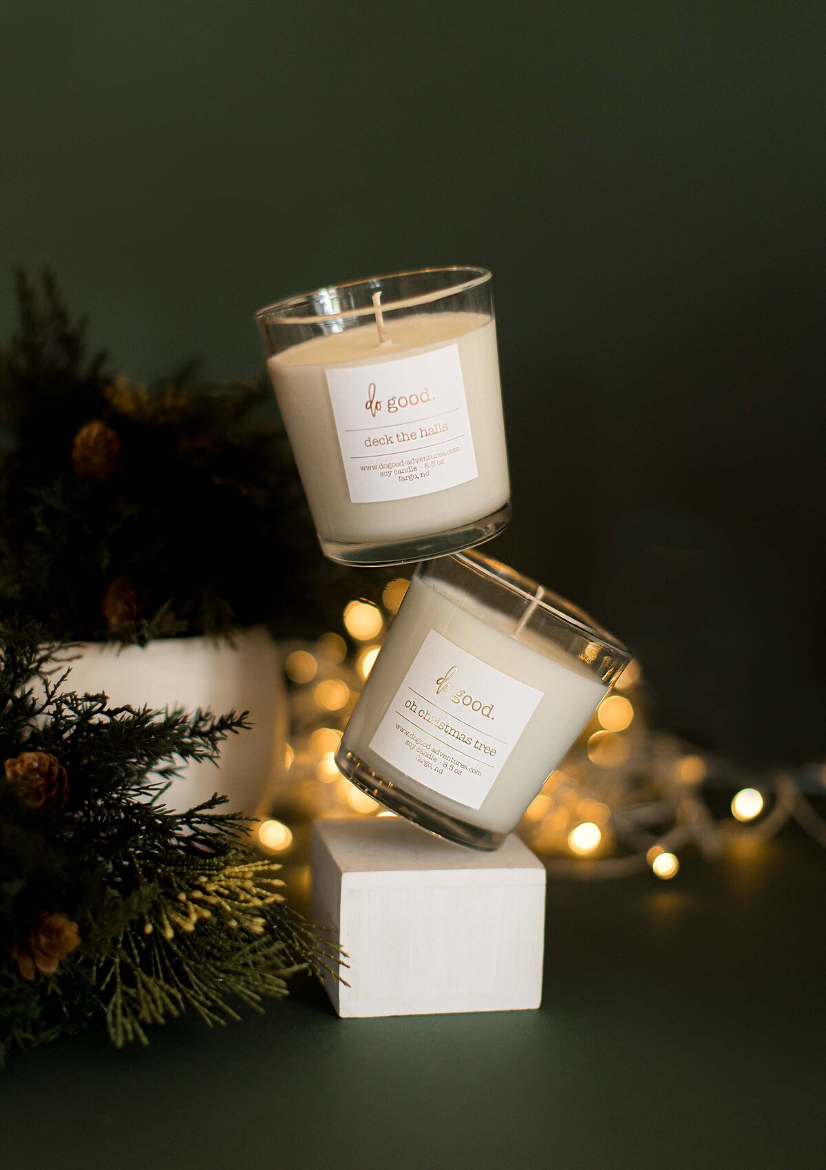 two stacked candles with Christmas lights in the background