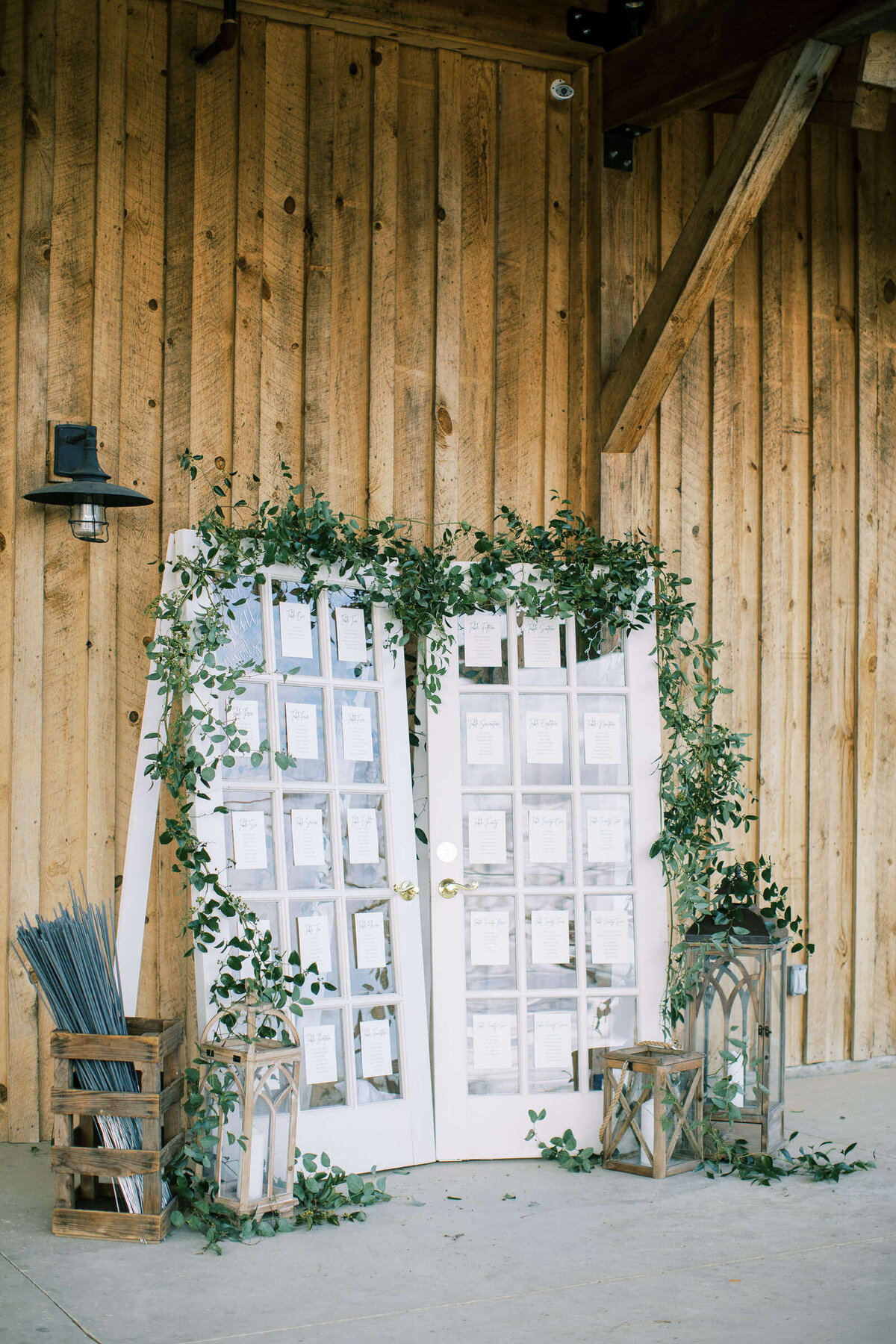 Rustic barn wedding seating arrangements on old doors with greenery