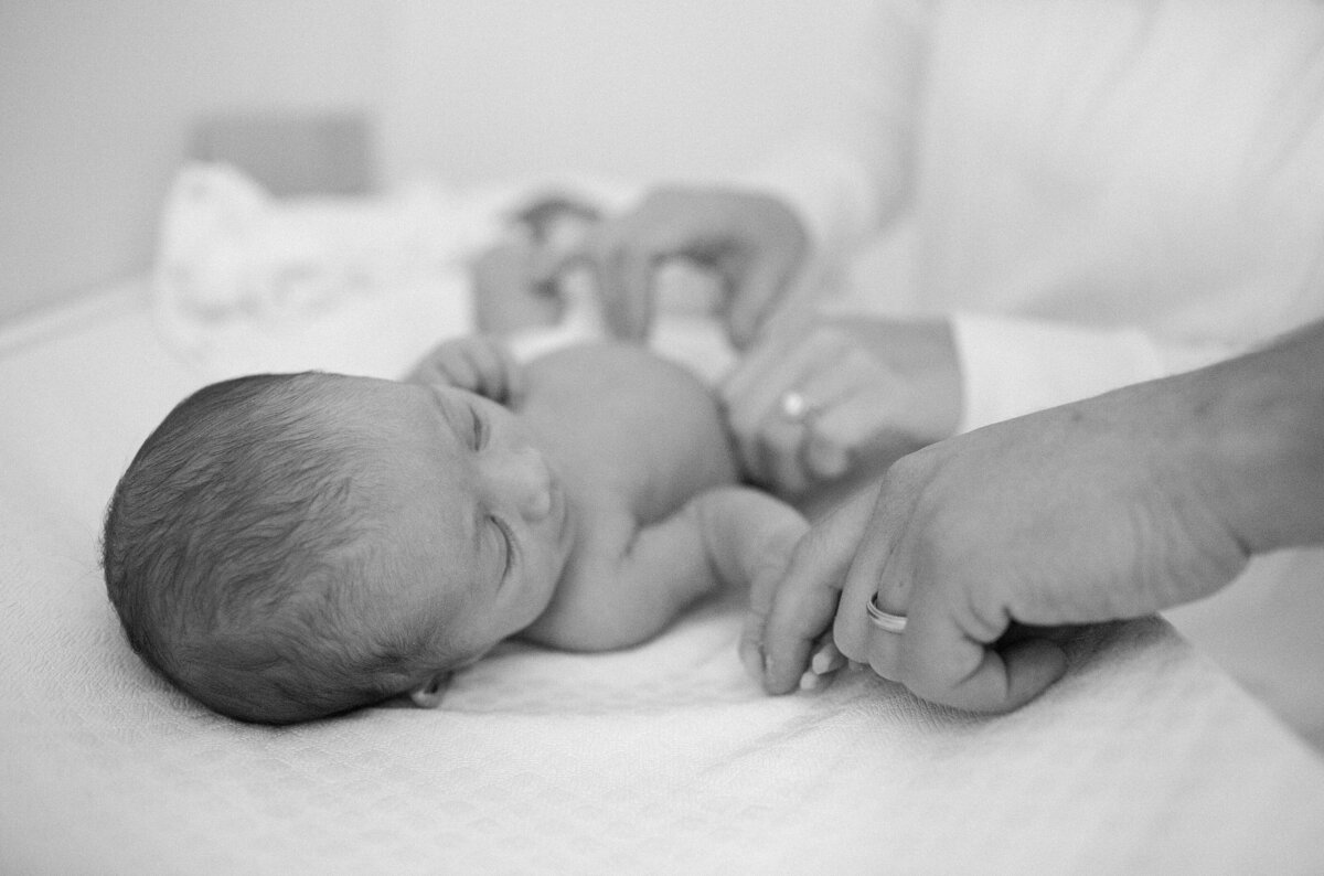 Father holds baby's hand during newborn session.