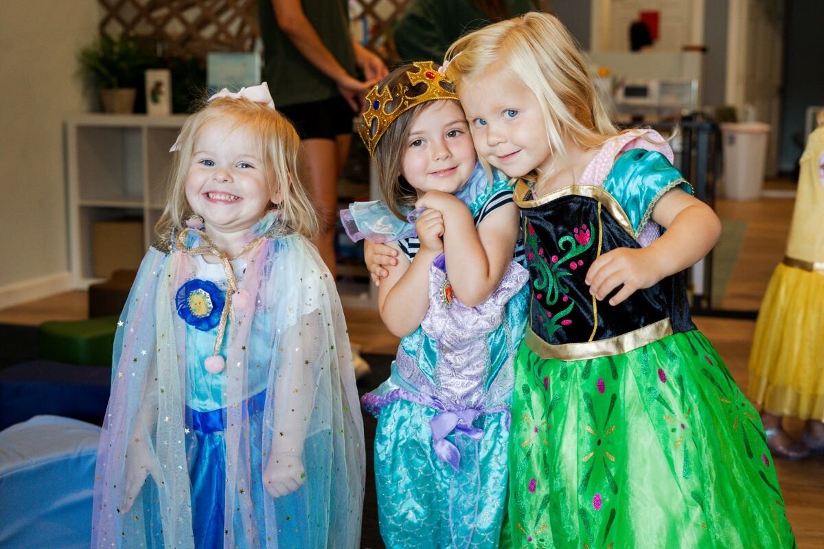 Three young students dressed up as princesses in the classroom playing at The Nest, a preschool and learning center in Surf City, North Carolina