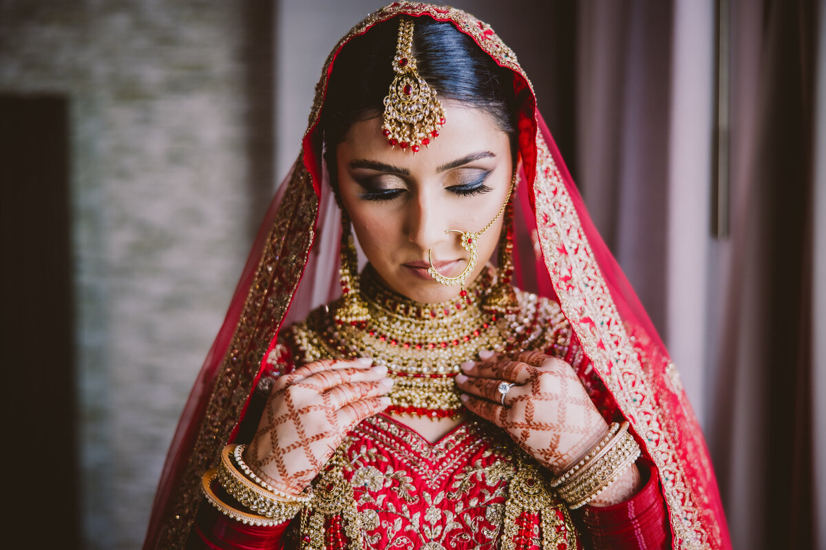 Sikh indian bride getting ready and adjusting her necklace before her anand karaj wedding ceremony in new jersey