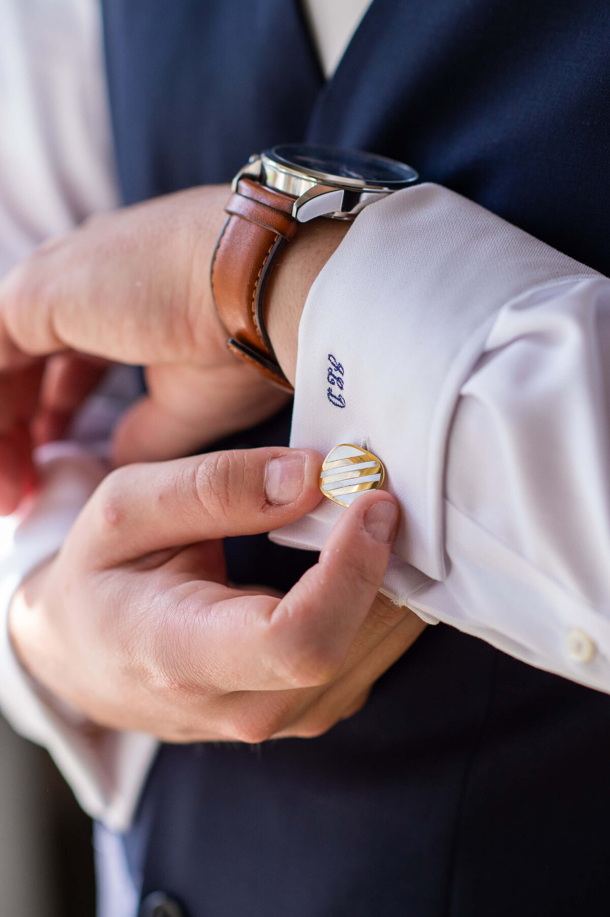 A groom adjusts his cufflink as he gets ready in the Badchild Pub  for his Ottawa weddingat at Stonefields Esate.