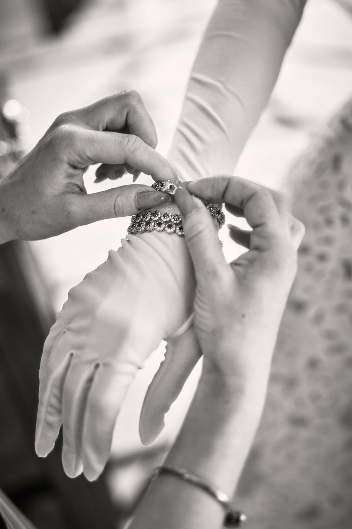 Gloved hand having help putting on jewlery