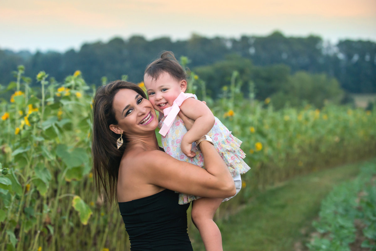 A mother and daughter enjoy their family photos in a sunflower field