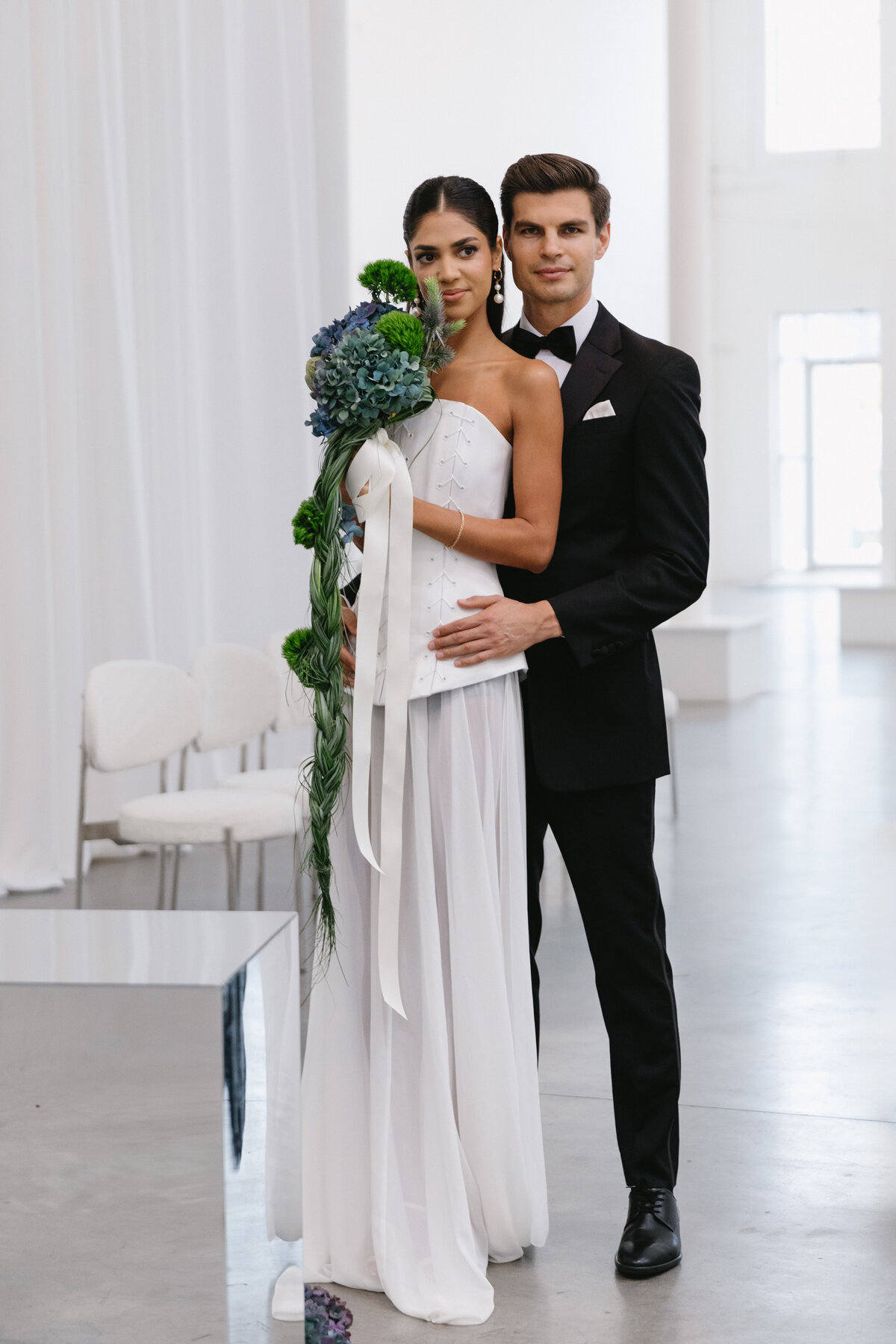Black and white portrait of bride and groom in a modern studio, showcasing their romantic connection and contemporary styling.