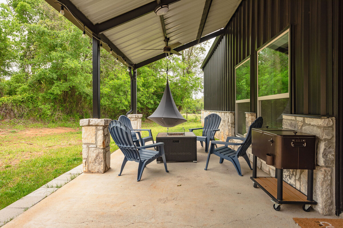 Covered outdoor entertaining area with firepit at this five-bedroom, 3-bathroom vacation rental house for up to 10 guests with free wifi, private parking, outdoor games and seating, and bbq grill on 2 acres of land near Waco, TX.
