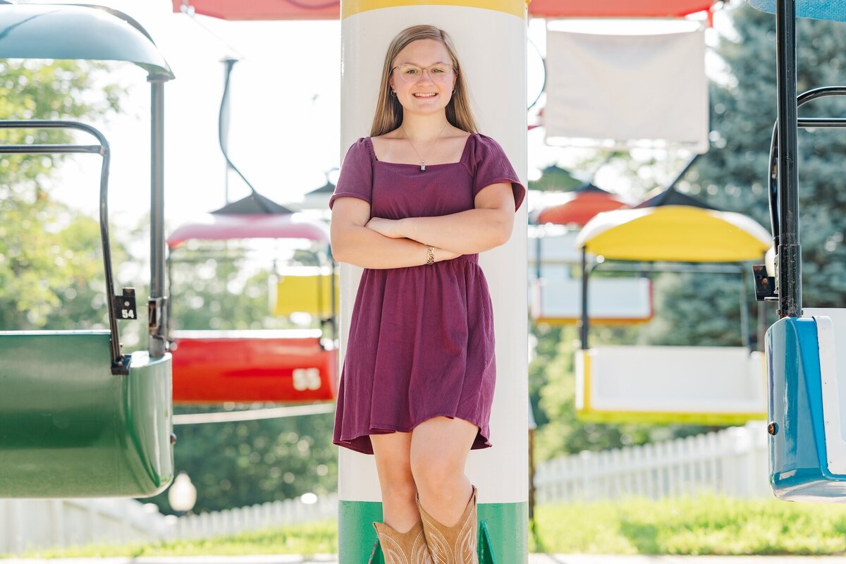 a girl in a burgundy dress standing in a merry go round