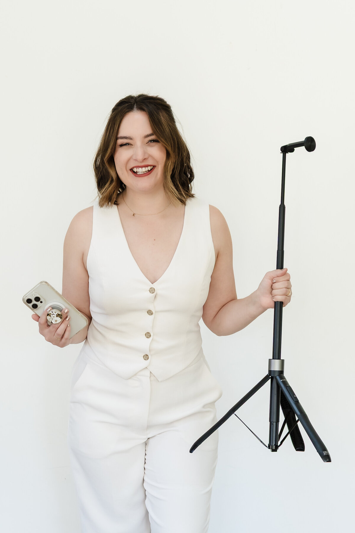 content creator posing holding a phone and a tripod