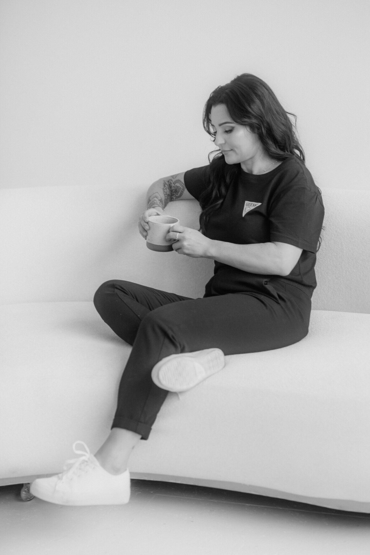 Relaxed woman on a sofa holding a cup and looking down