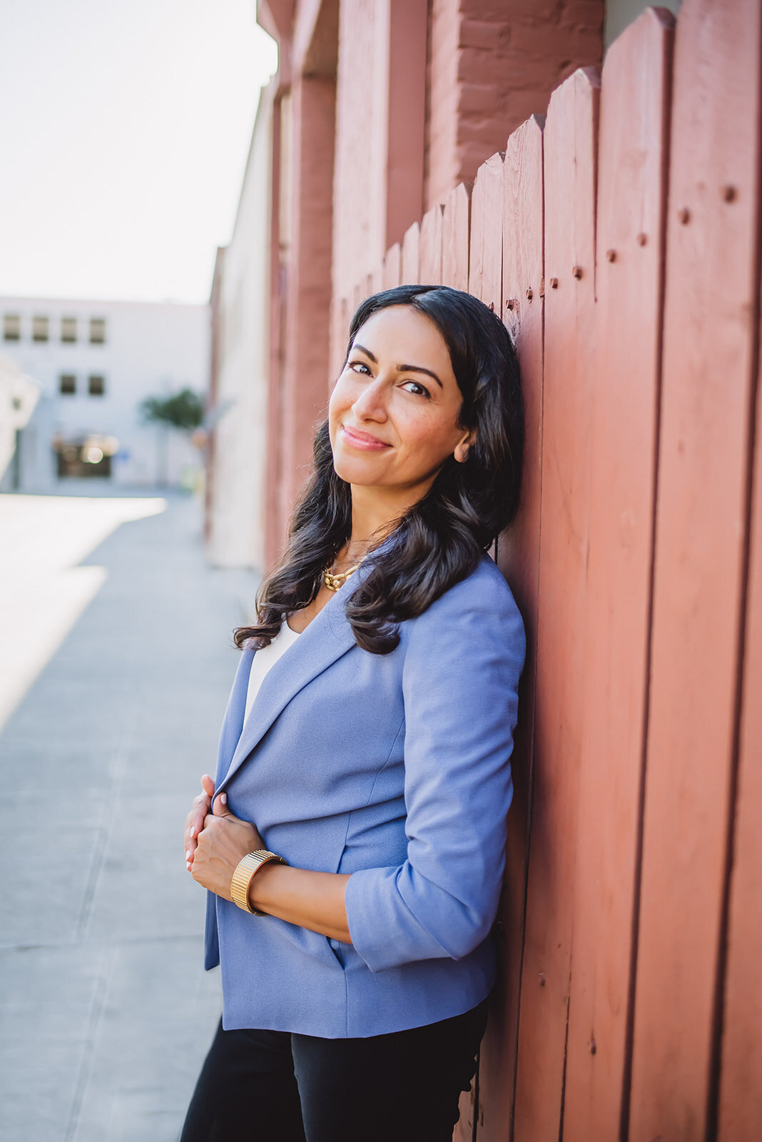 Hajar pulls her blue blazer together and smiles softly for headshots in Los Angeles.
