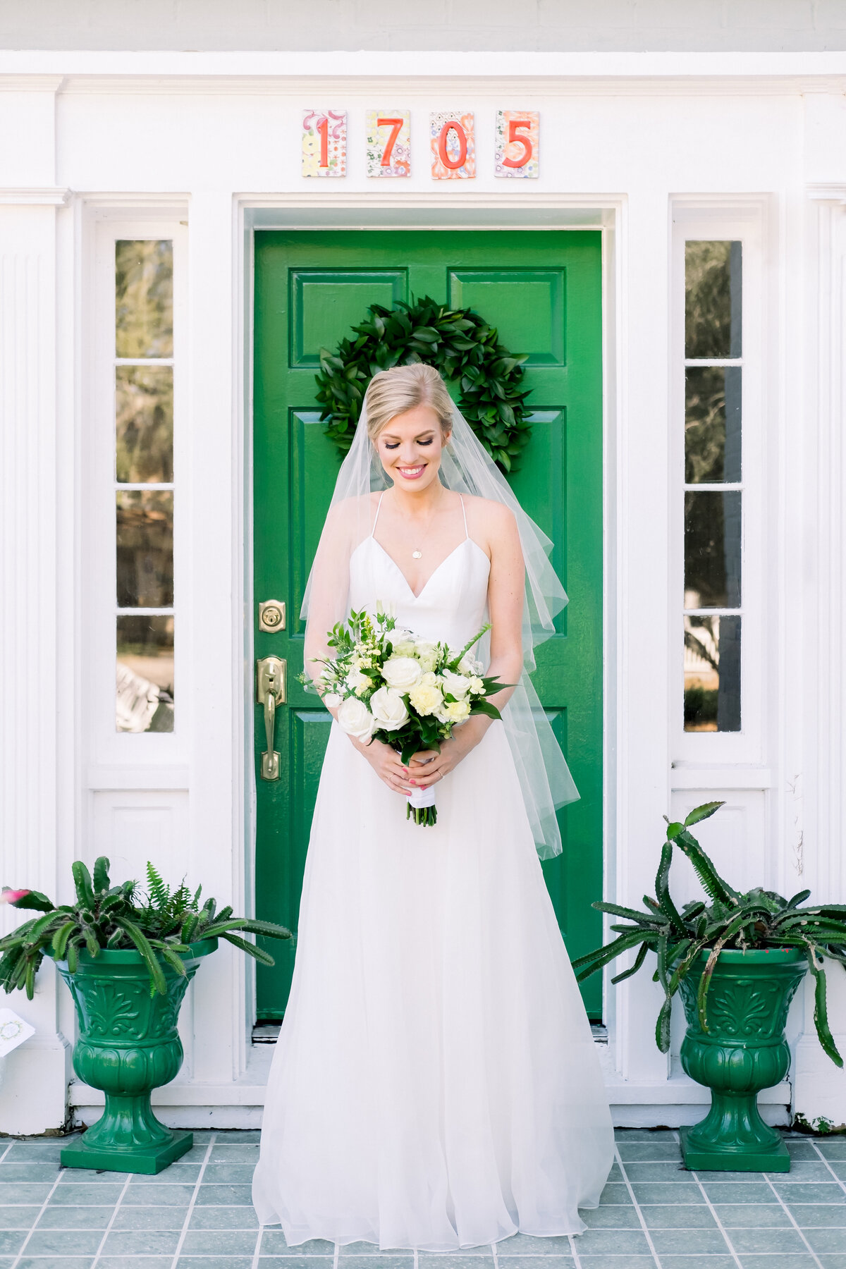 Bride standing in front of her childhood home's green front door in Palmetto, Florida