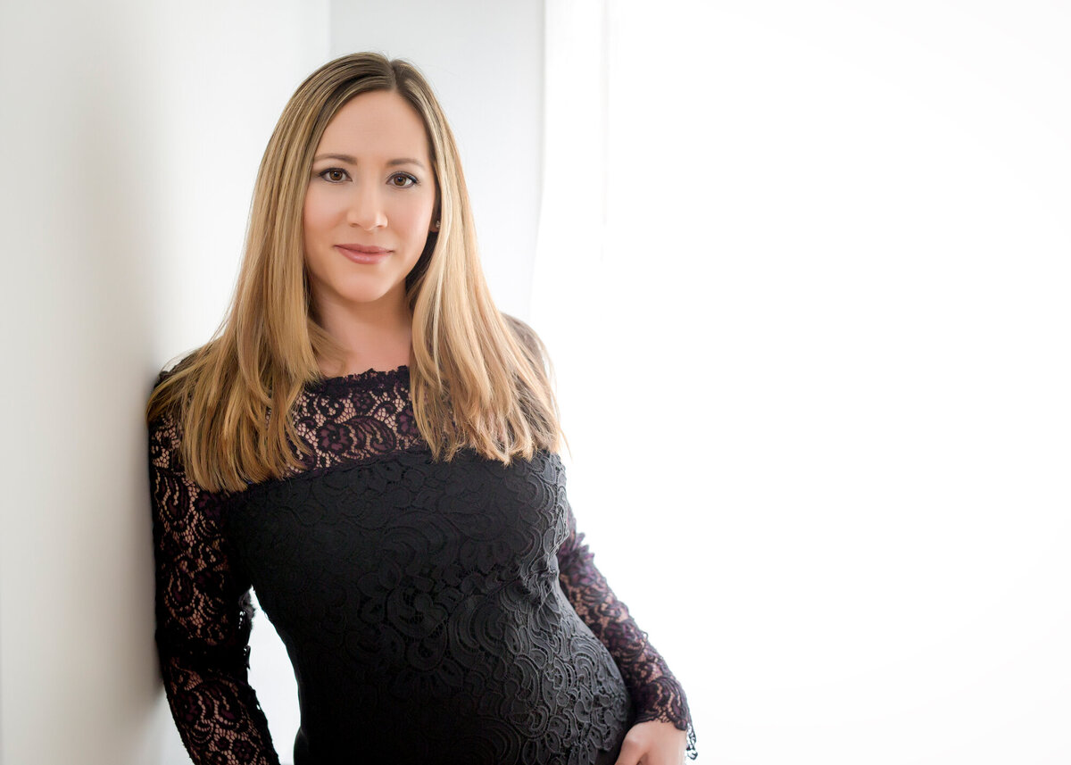 Female headshot client wearing a black lace dress leaning up against a wall