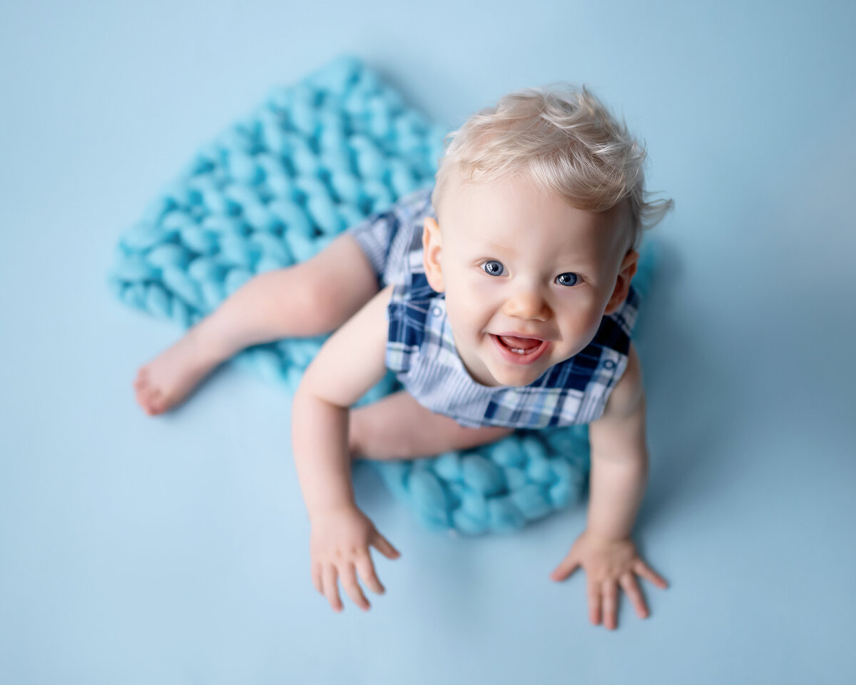 A curly headed boy smiles big at his Iowa Milestone Photographer