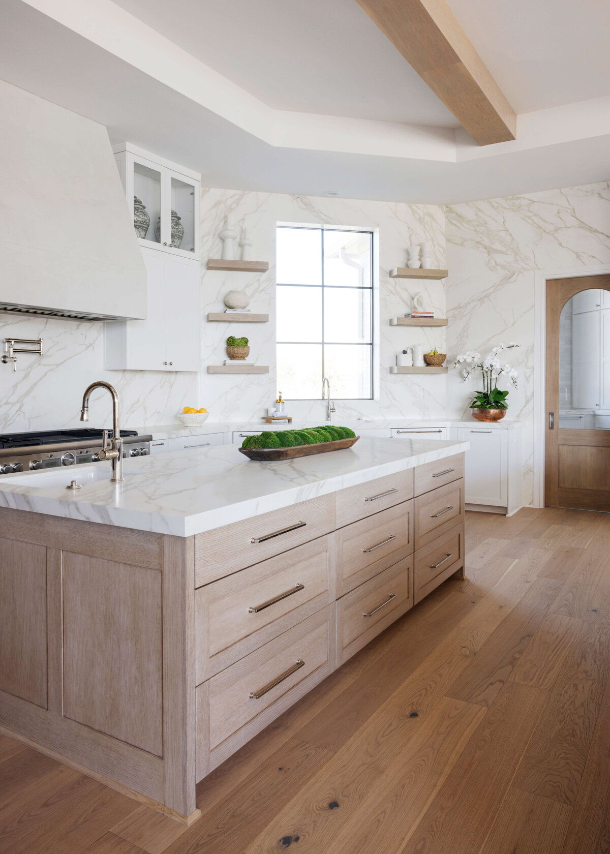 oyster creek studios hughes white marble walls light wooden cabinets shelving in kitchen