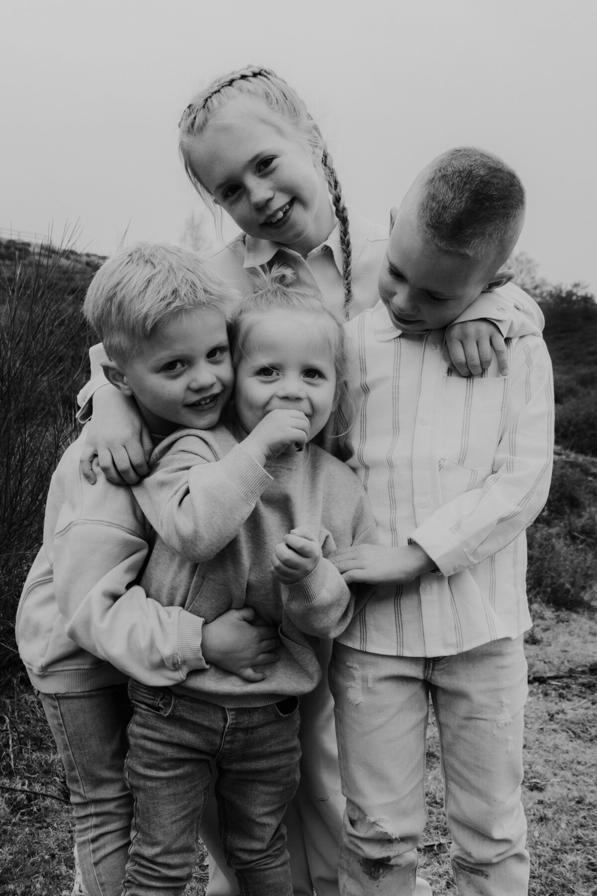  Drie kinderen omhelzen elkaar in een zwart-witfoto, stralend van vreugde en verbondenheid.