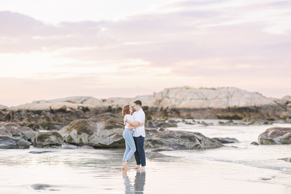 Couple kissing in front of rocks at Wingaersheek Beach
