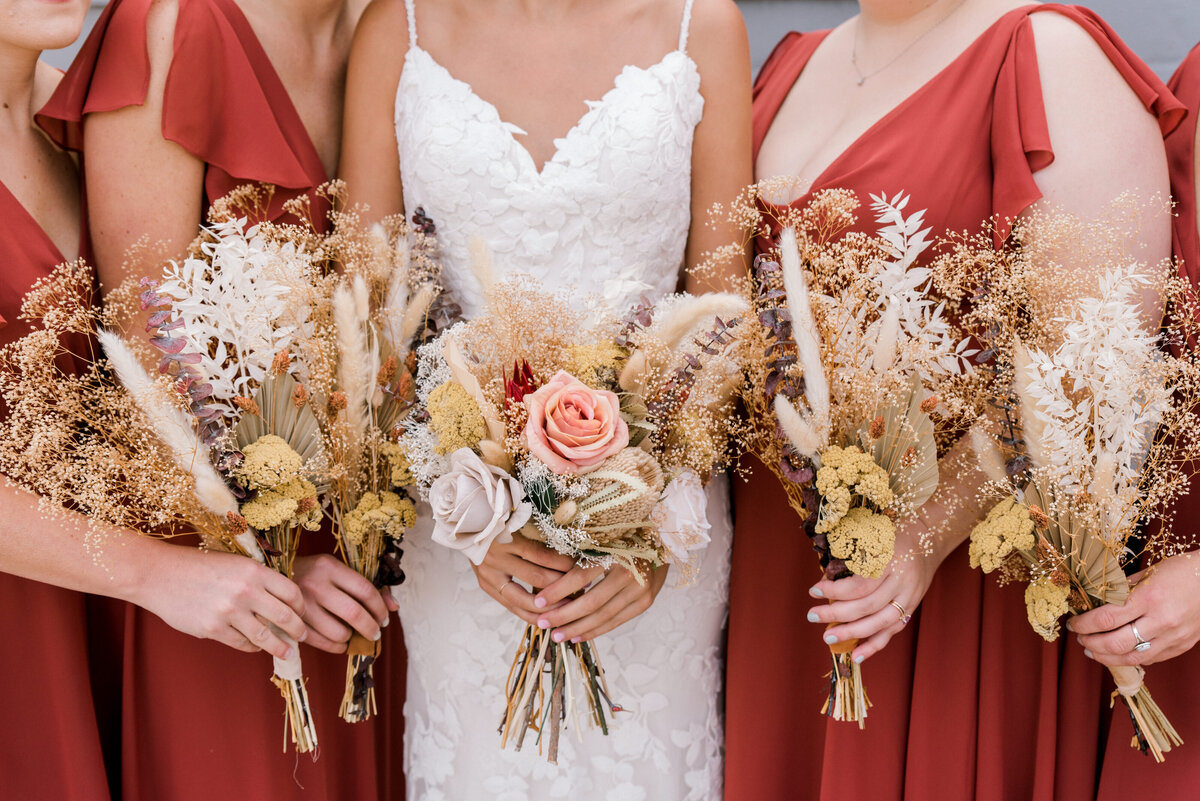 Bride and bridesmaids stand together holding bouquets