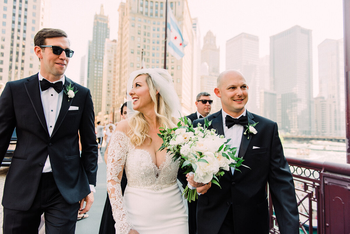 A candid moment of a bride and groom with their wedding party crossing the Michigan Avenue Bridge, with Chicago’s skyline in the background.