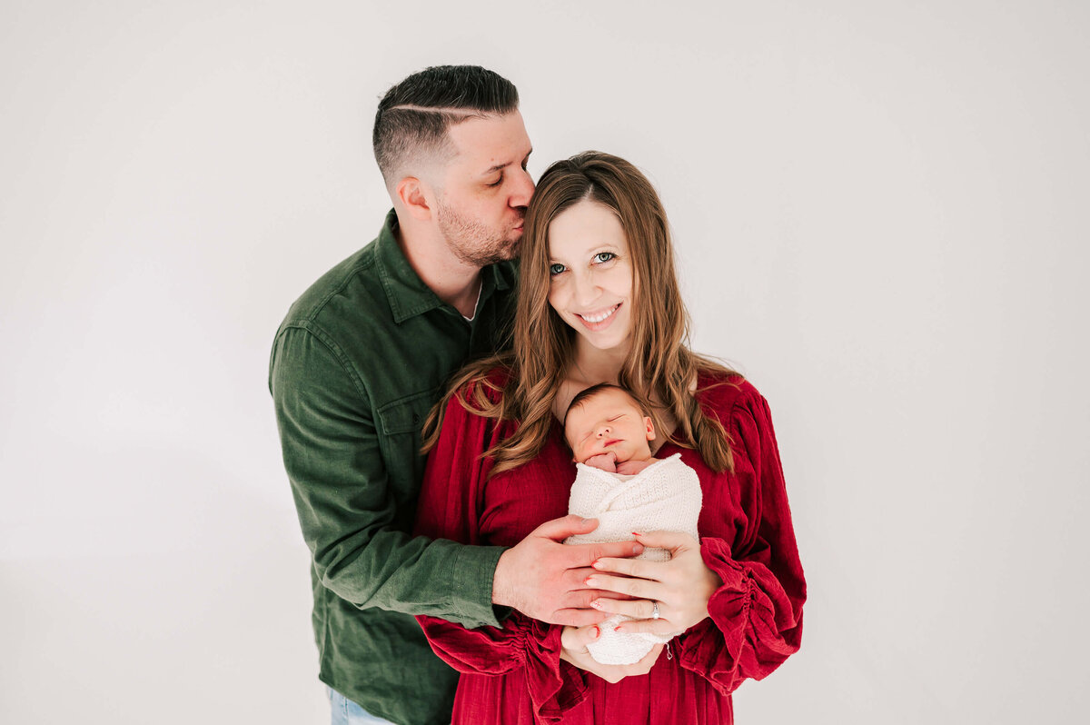 parents cuddling holding baby in white Springfield MO newborn photogrpahy studio