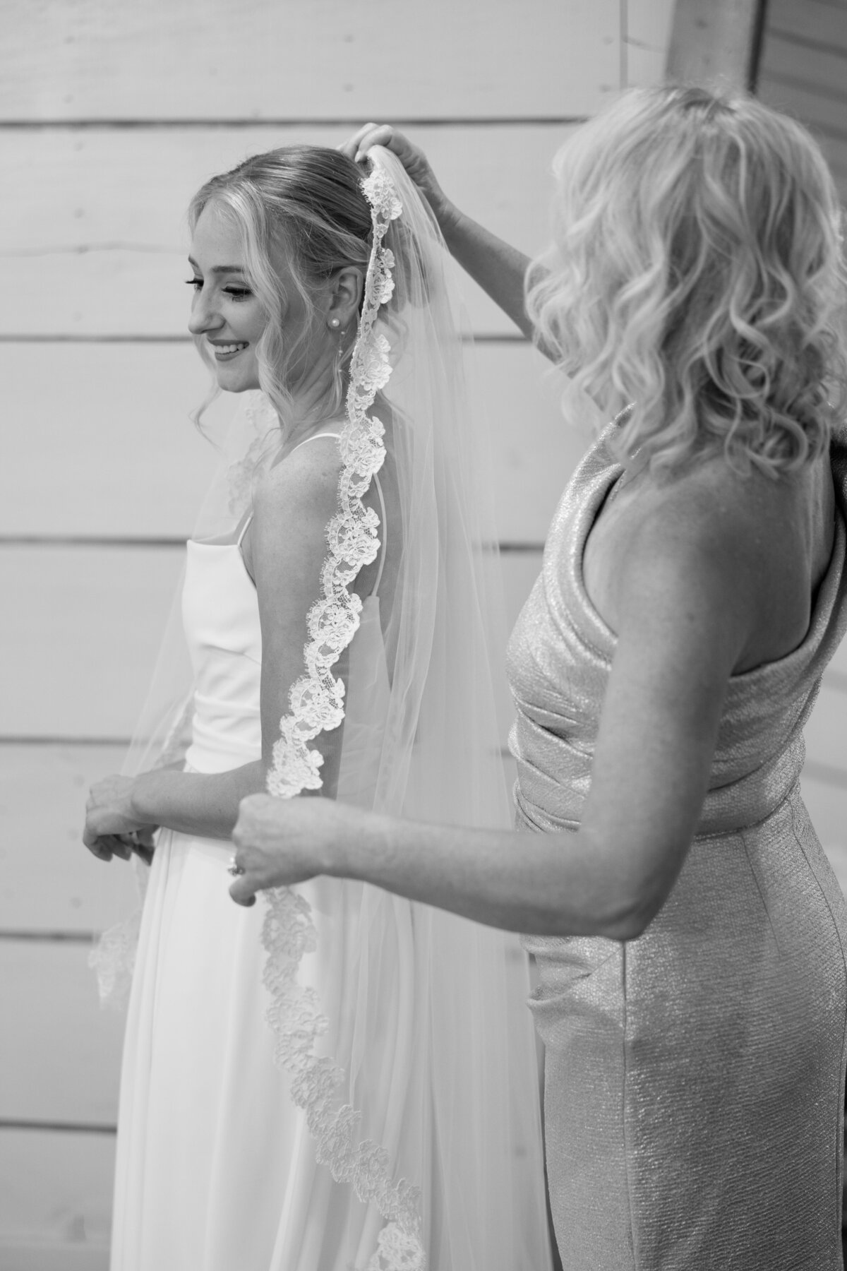 Mother of the bride assists the bride with her veil.