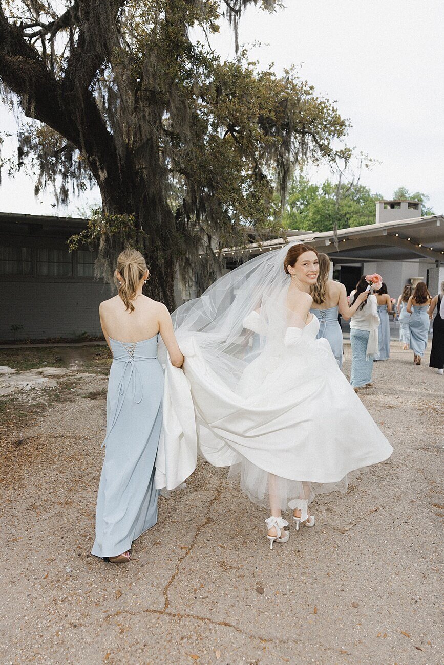 bride and bridesmaids walking away as the bride looks back