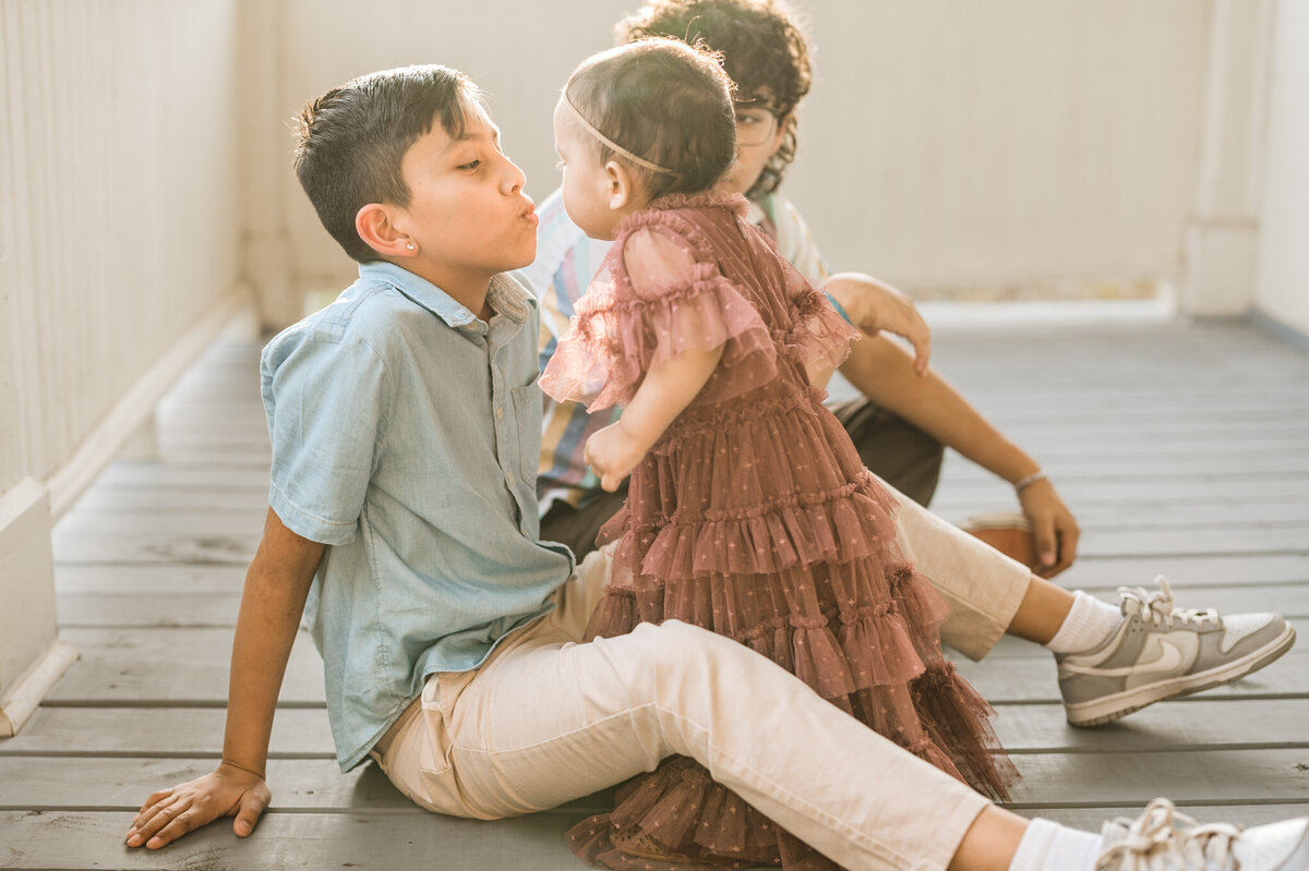 Little sister leans in to kiss her big brother during family pictures in San Antonio.