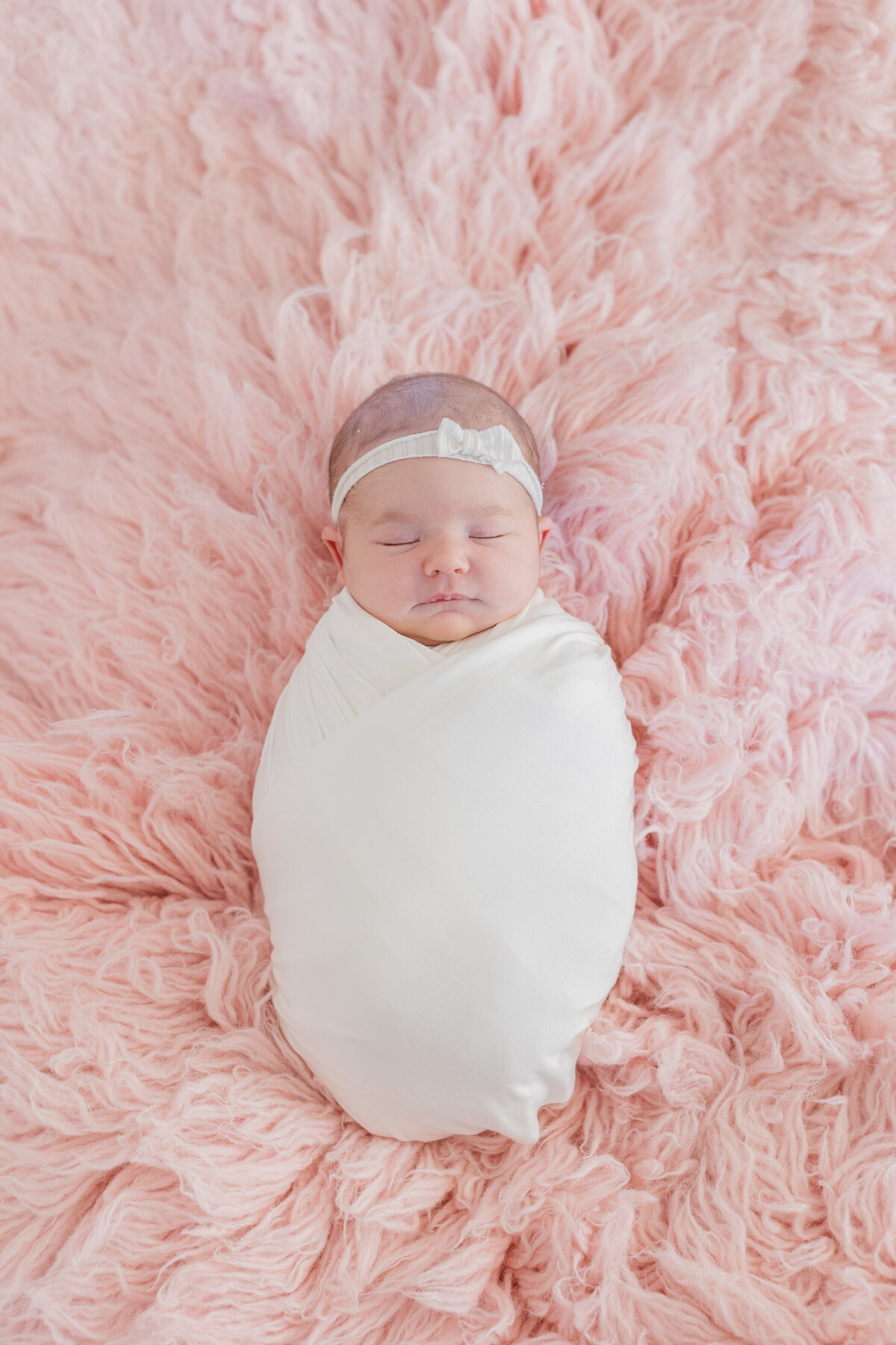 Newborn sleeping under a pink flokaki