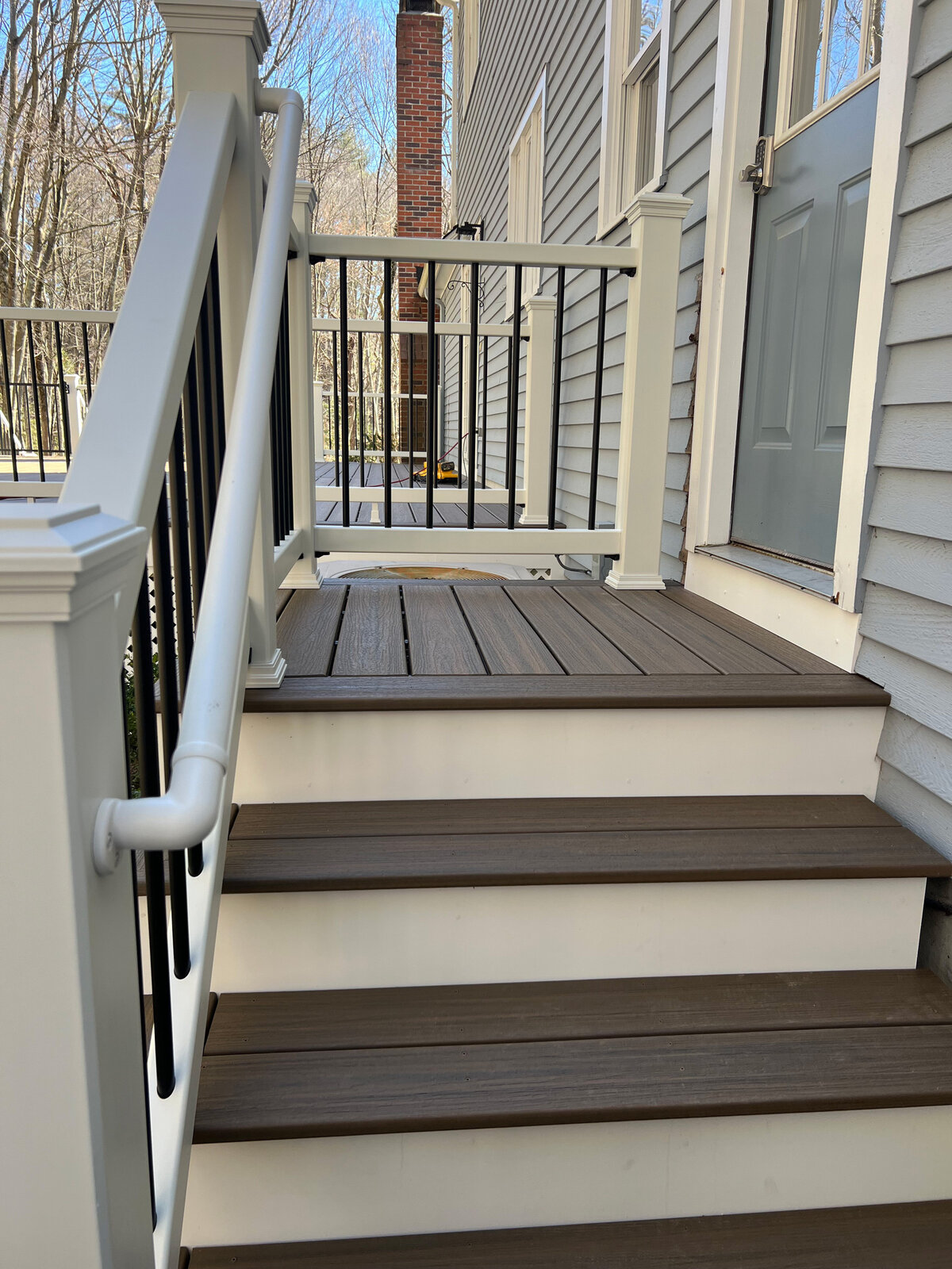 Set of stairs for side doow with dark brown composite and white rise on steps