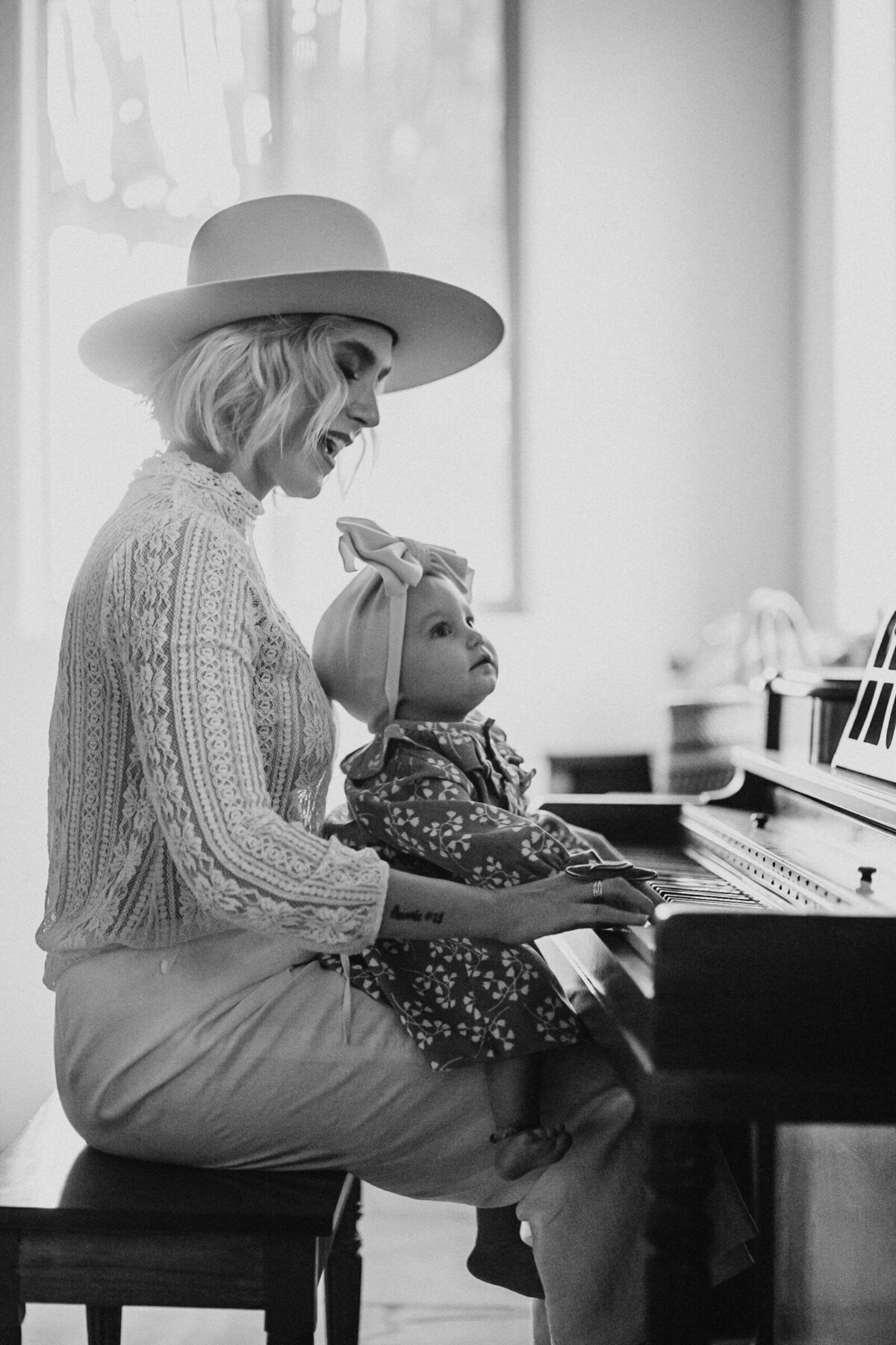 black and white photo of mother and daughter playing the piano together in their home