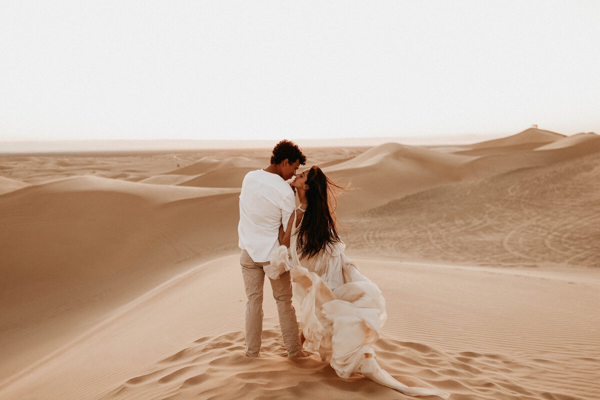 couple walking through sand dunes