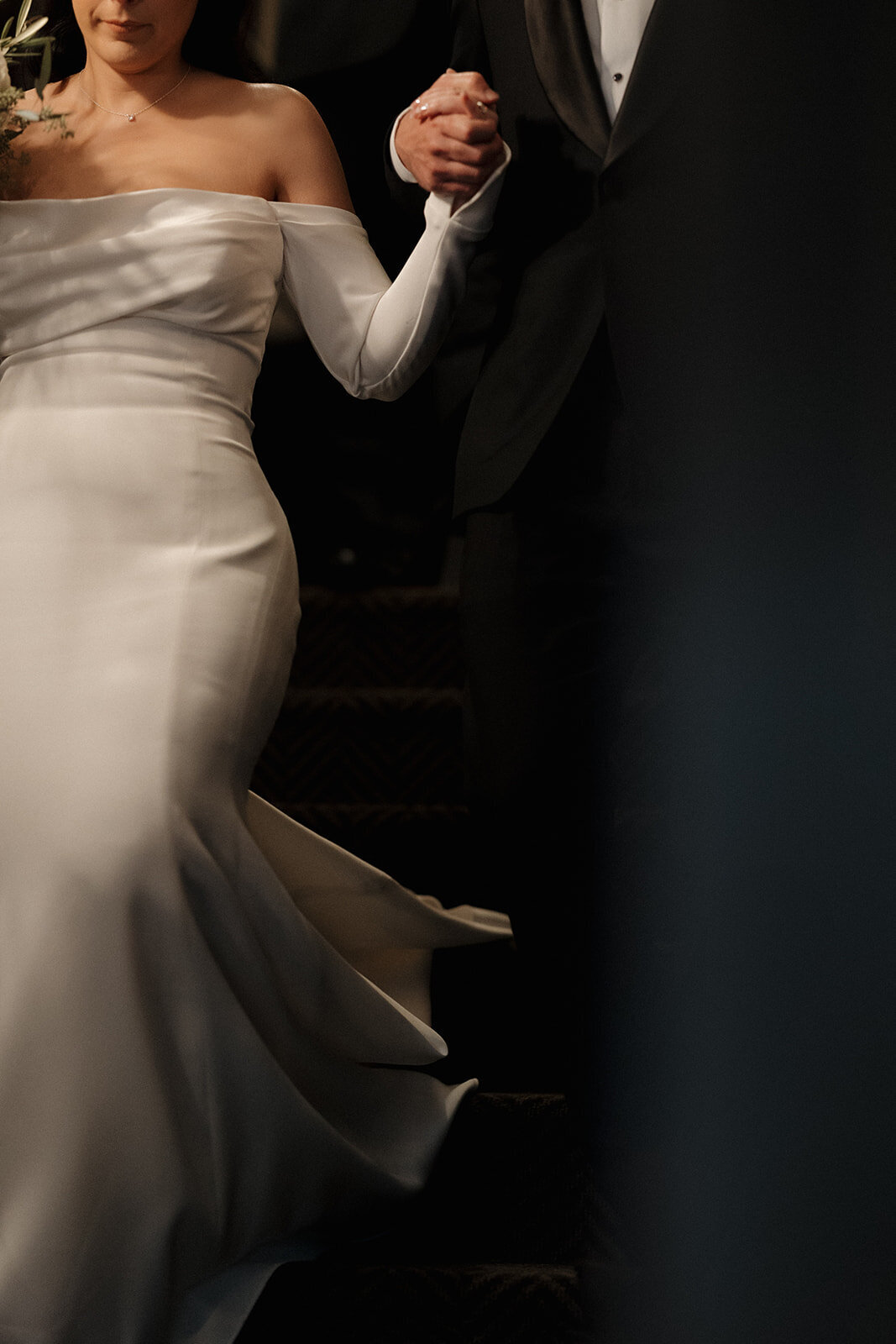 Documentary wedding photography capturing a bride elegantly descending stairs, showcasing her luxurious gown and intimate moment.